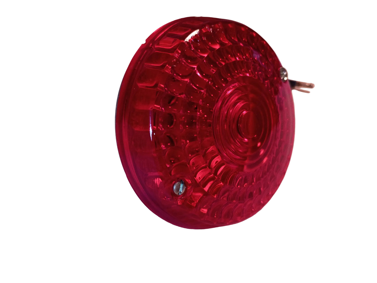 A red circular plastic vehicle light or reflector with a textured, ridged surface and a small metal terminal on the side, resting on a light-colored fabric surface.